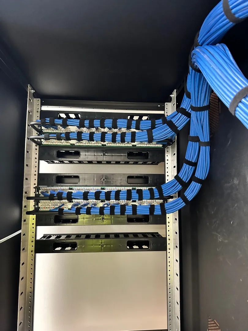 Wall-mounted network rack with dressed blue Cat6 patch cabling at a Data Pro Communications project in Orlando, FL
