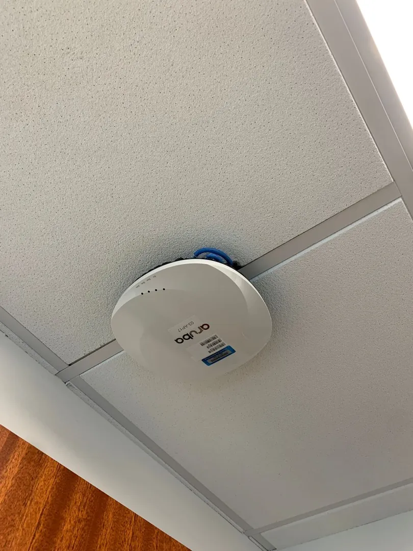 Ceiling access point on a drop-ceiling grid near wood paneling at a Data Pro Communications project in Orlando, FL