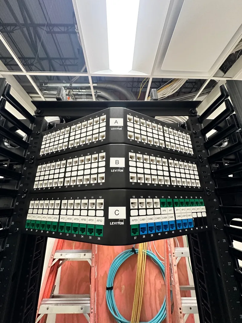 Labeled A, B and C patch panel rows on open racks with fiber below at a Data Pro Communications project in Orlando, FL