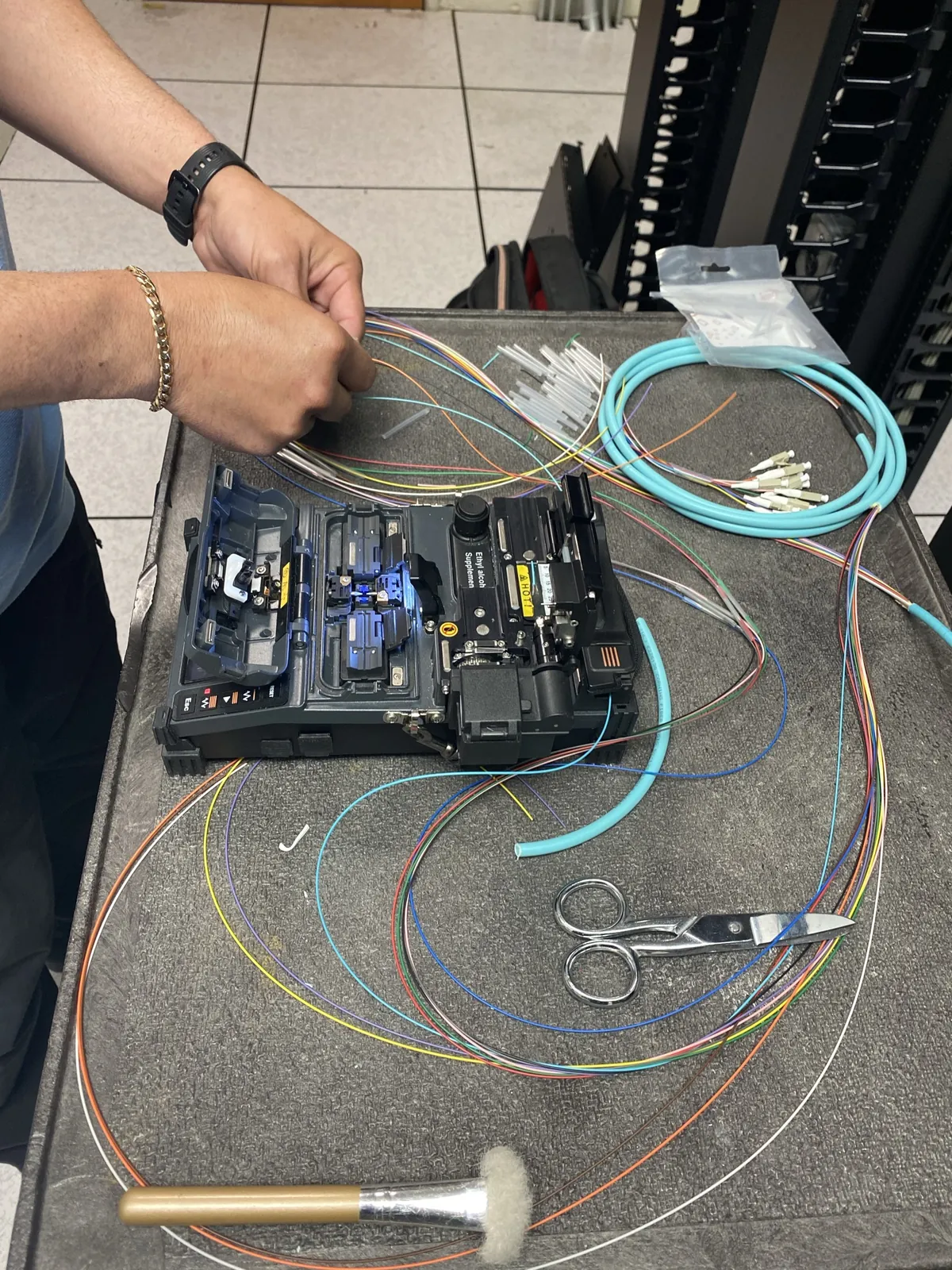 Technician preparing fiber strands beside a fusion splicer at a Data Pro Communications project in Orlando, FL