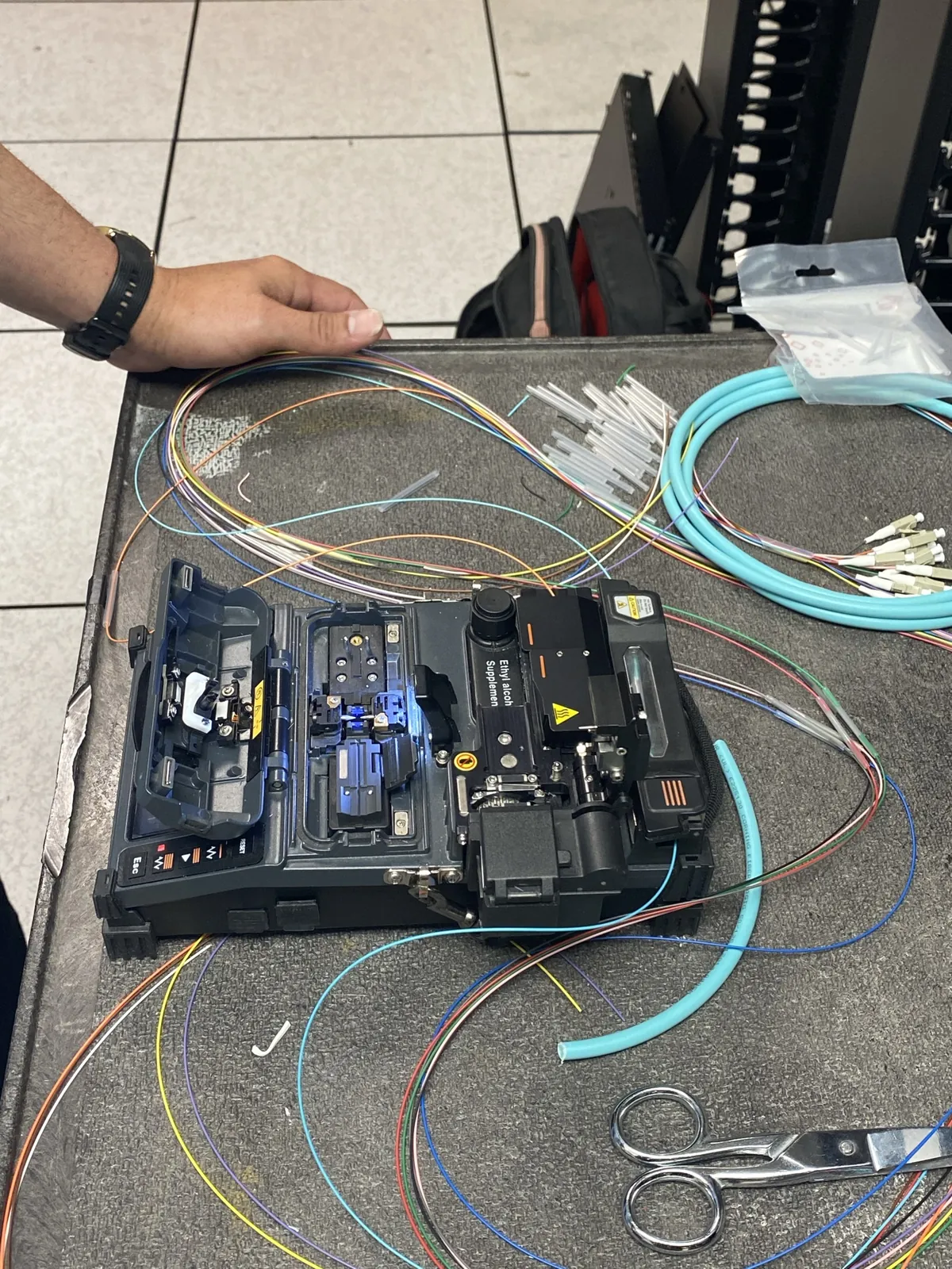 Fusion splicer and color-coded fiber strands on the work surface at a Data Pro Communications project in Orlando, FL