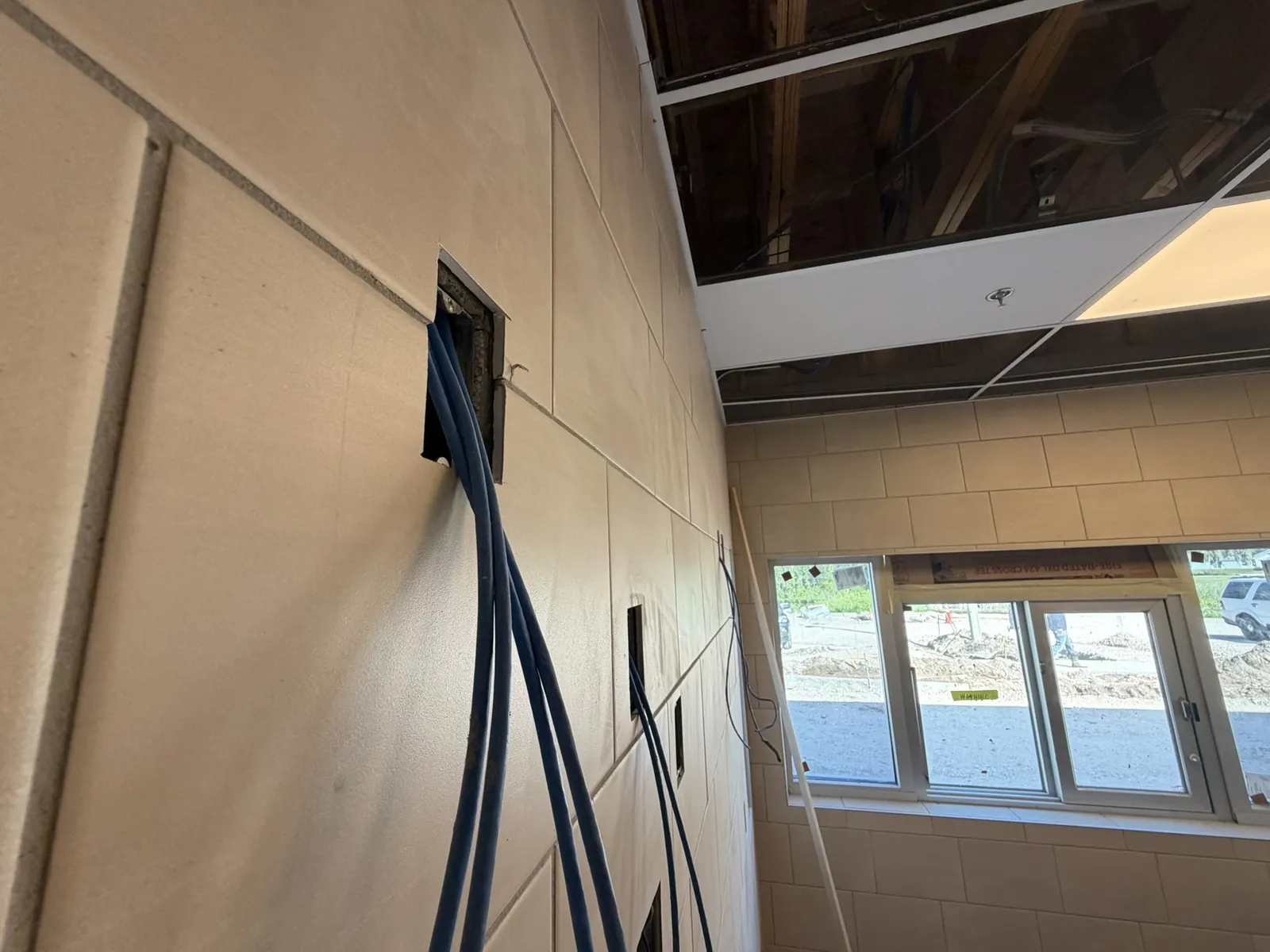 Close-up of structured cabling rough-in entering a wall opening at a Data Pro Communications project in Orlando, FL