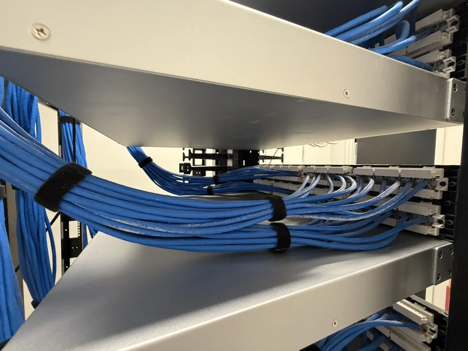 Blue cable bundles dressed onto rack shelving at a Data Pro Communications project in Orlando, FL