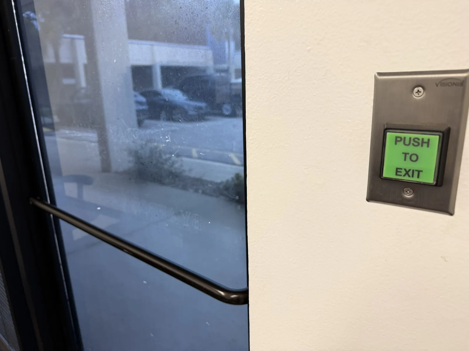 Push-to-exit button beside a glass entry door at a Data Pro Communications project in Orlando, FL